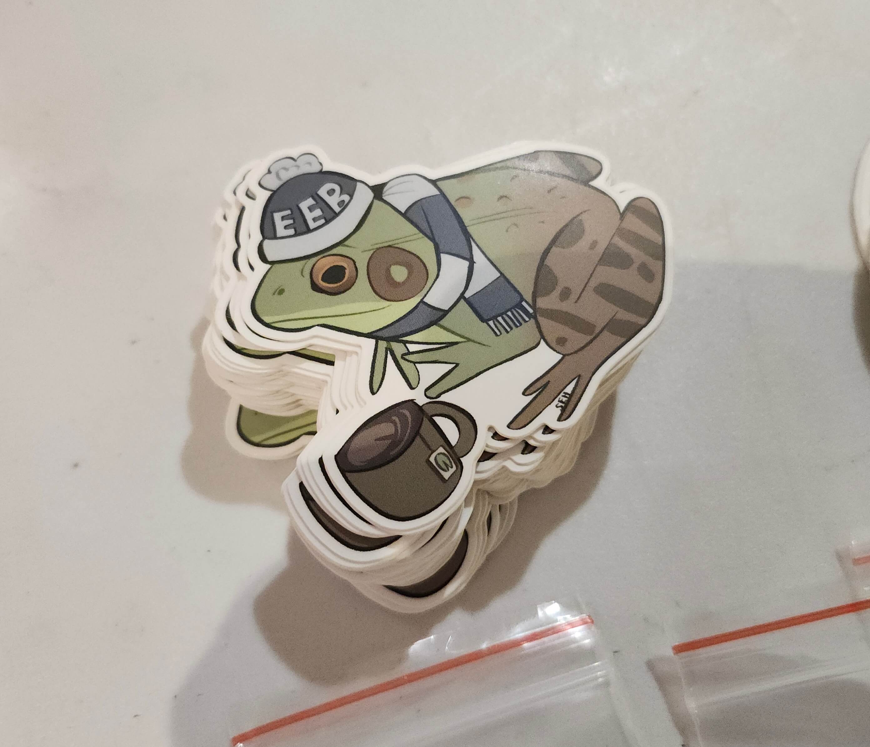 A photograph of a sticker design with a frog in a hat.