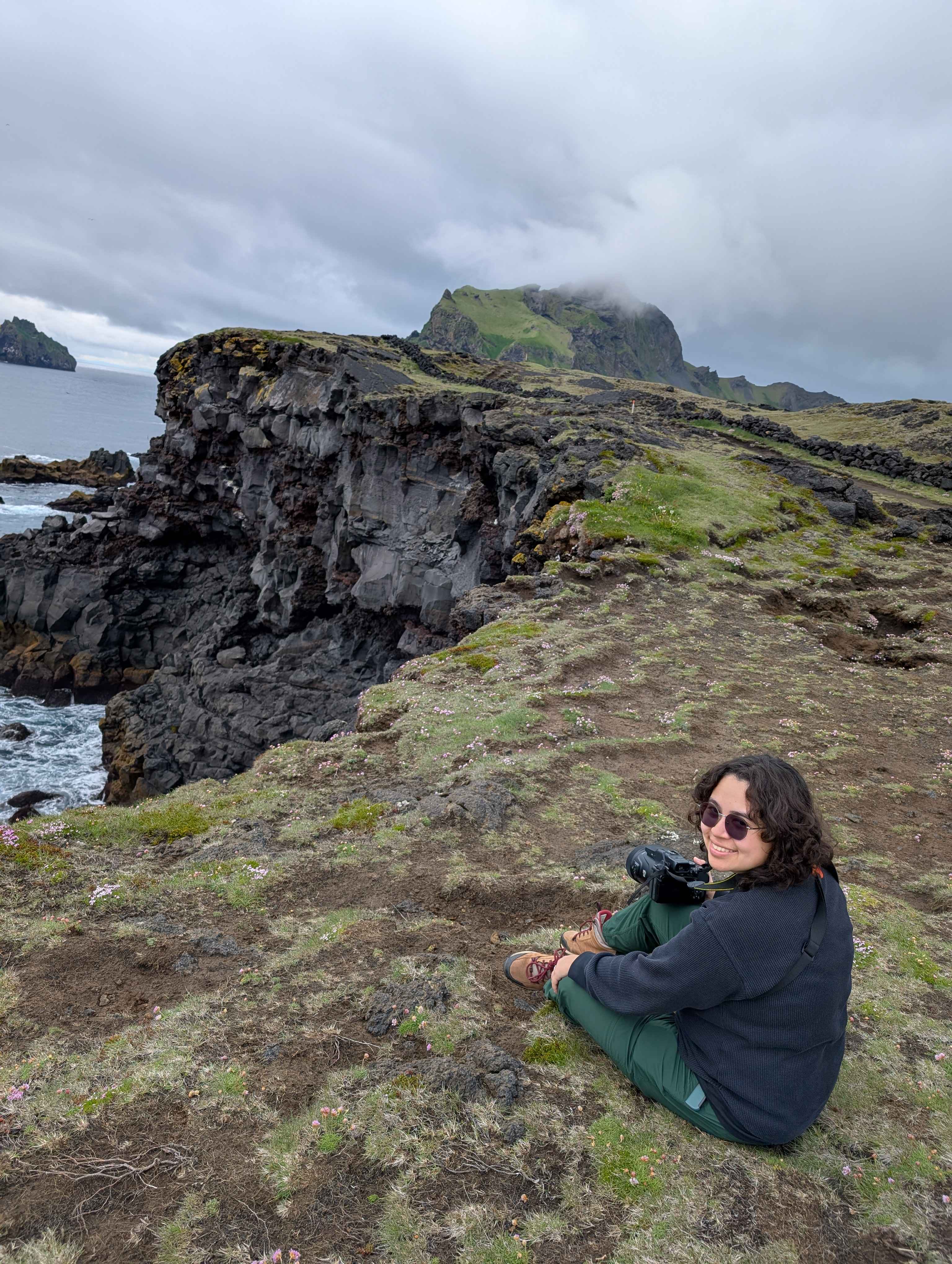 Photograph of a person sitting next to a cliff.